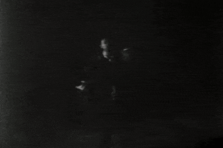 a black and white photo of a man holding a gun in a room .
