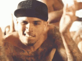 a shirtless man wearing a hat and a tattoo on his chest is sitting on a bed .