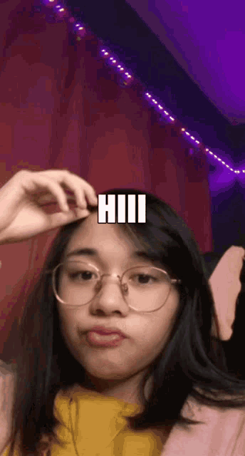 a girl wearing glasses and a yellow shirt has the word hii on her forehead