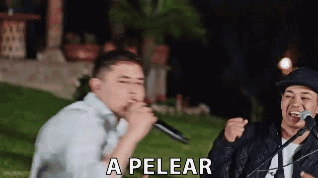 a man is singing into a microphone while another man laughs .
