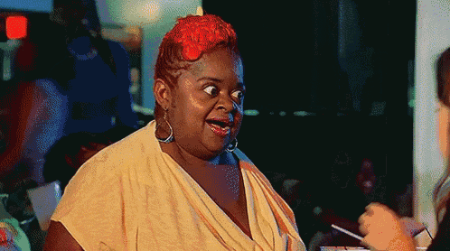 a woman with red hair is making a funny face while sitting at a table .