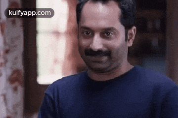 a man with a mustache is making a funny face while wearing a blue shirt .