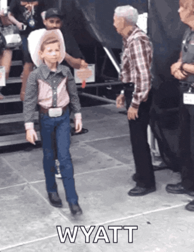 a young boy in a cowboy outfit is standing next to a man in a plaid shirt with the word wyatt on the floor