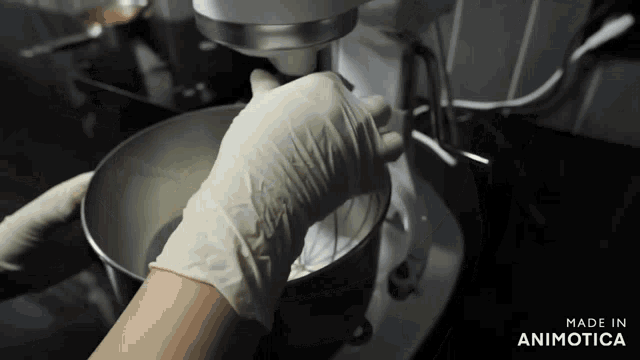 a person wearing white gloves is mixing something in a mixer that is made in animatica