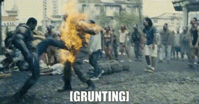 a group of people are fighting each other on a street with a man on fire .