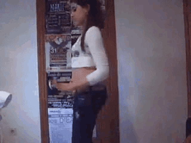 a woman is standing in front of a door with a bunch of posters on it .