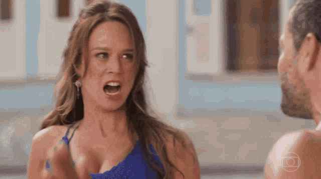 a woman in a blue dress is yelling at a man without a shirt