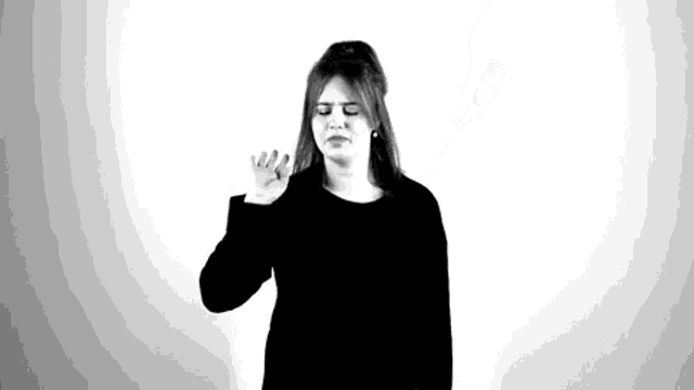 a black and white photo of a woman making a funny face with her eyes closed .