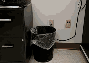 a black trash can with a plastic bag in it