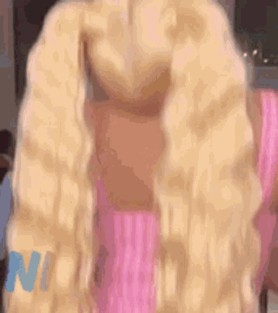 a close up of a woman with blonde hair wearing a pink shirt .