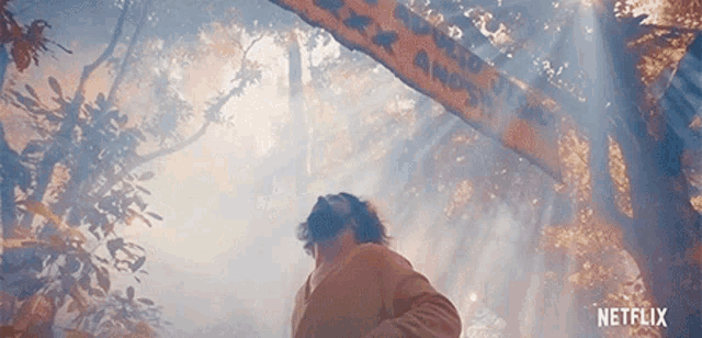 a man is standing in a forest under a sign that says netflix