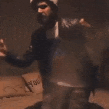 a man is dancing in a dark room with his hands outstretched .