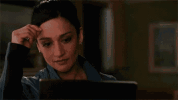 a woman is sitting at a table looking at a laptop .