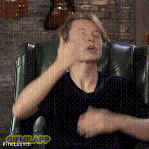 a man is sitting in a chair making a funny face with his hand .