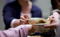 a group of people are toasting with cups of liquid .