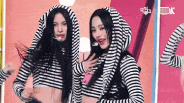 two women are standing next to each other wearing striped shirts with a hood .