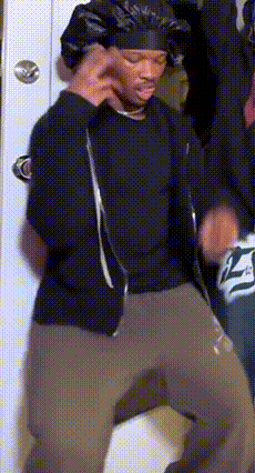 a man wearing a bandana and a black shirt is dancing in a room .