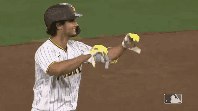a baseball player wearing a padres uniform and gloves is looking up at the sky .