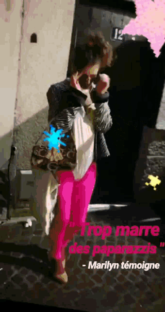 a woman wearing bright pink pants is standing in front of a building with the number 12 on it
