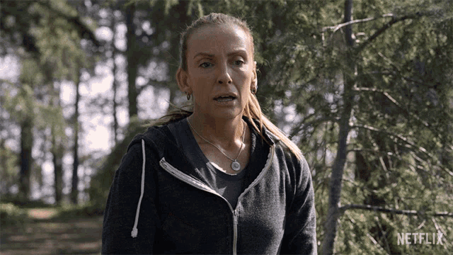 a woman standing in the woods with a netflix logo on the bottom