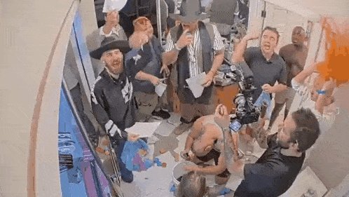a group of men are standing around a man in a bathroom .