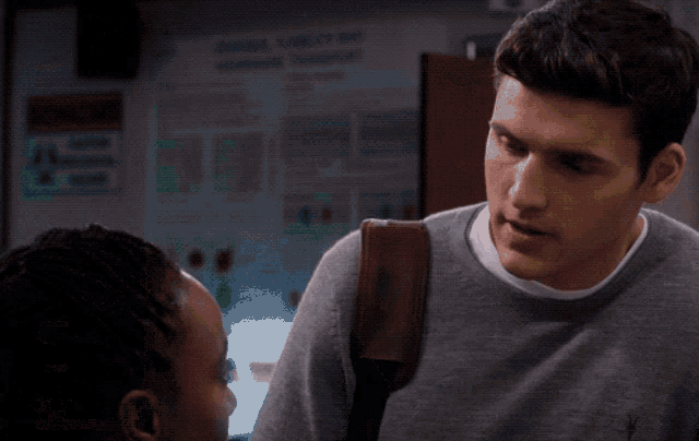 a woman in a white shirt and green vest looks at a man