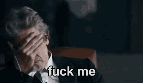 a man in a suit and tie is covering his face with his hand and the words `` fuck me '' written below him .