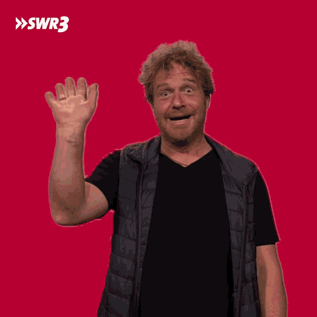a man waves his hand in front of a red background with the letters swr3