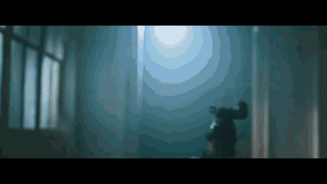 a person standing in a dark room with a light coming through the window