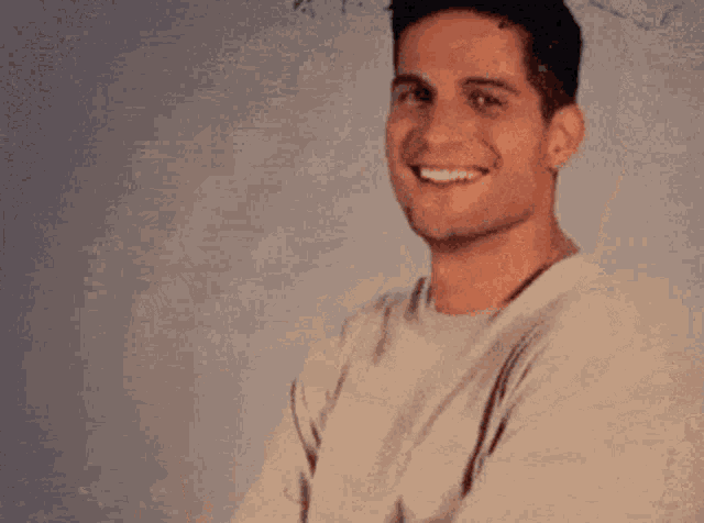 a young man in a white shirt is smiling for the camera