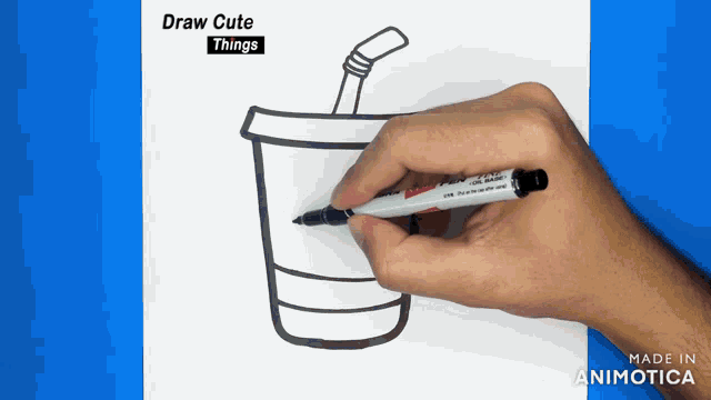 a person is drawing a cup with a straw on a piece of paper