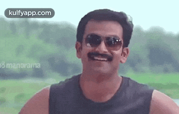 a man with a mustache is wearing sunglasses and smiling .