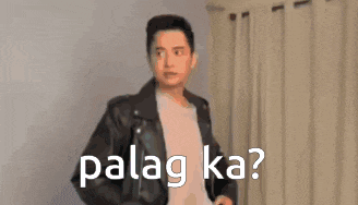 a man wearing a leather jacket and a white shirt is standing in front of a curtain with the words palag ka .