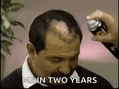 a man with a mustache is getting his hair sprayed with a spray can .