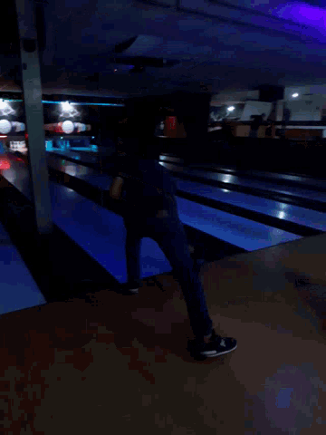a man is standing in a bowling alley with a cone in the foreground