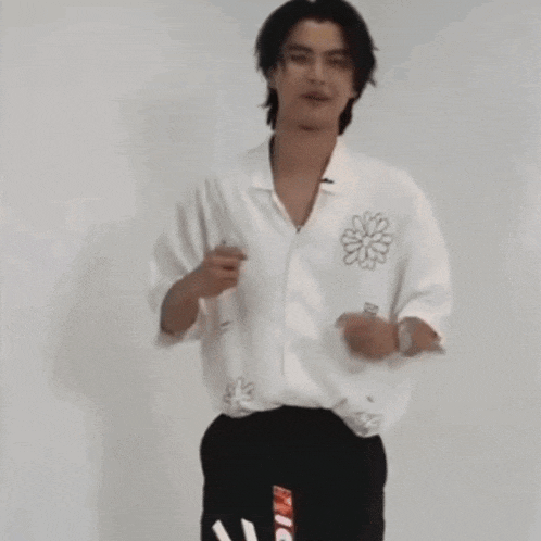 a young man wearing a white shirt and black pants is dancing .