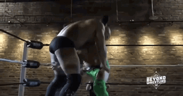two men are wrestling in a wrestling ring with the words beyond wrestling on the bottom .