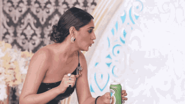 a woman in a black dress is holding a green can of diet coke