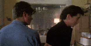 two men are standing in a kitchen looking at each other