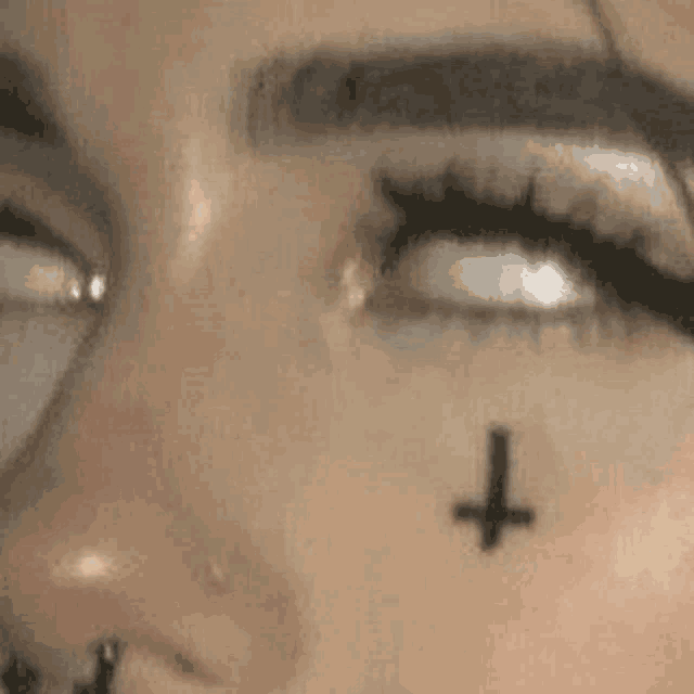 a close up of a person 's face with a cross on their face .