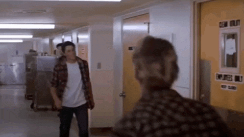 a man and a woman are standing in a hallway and talking to each other .