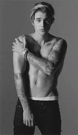 a black and white photo of a shirtless man with tattoos on his arms and chest .