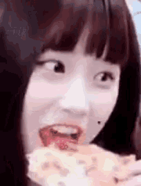 a close up of a woman eating a slice of pizza with her tongue out .