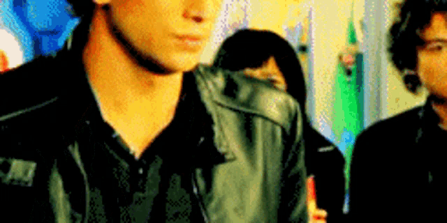 a man wearing a black leather jacket is standing in front of a woman .