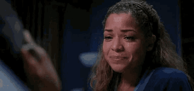 a woman is crying with a tear coming out of her eye while talking on a cell phone .