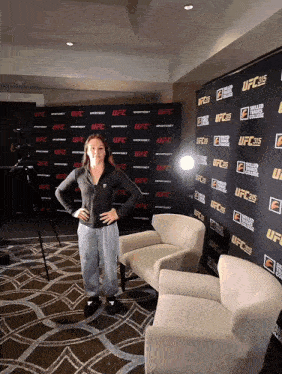 a woman stands in front of a wall that says ufc on it