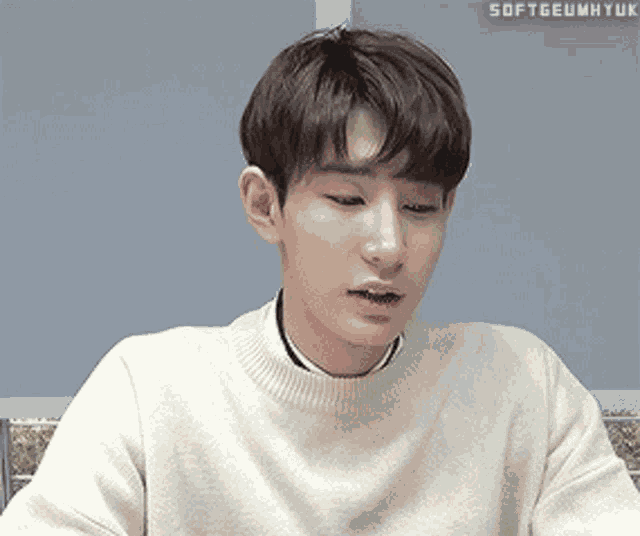 a close up of a young man wearing a white sweater