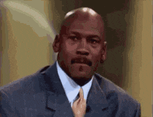 michael jordan is wearing a suit and tie while talking on a television show .