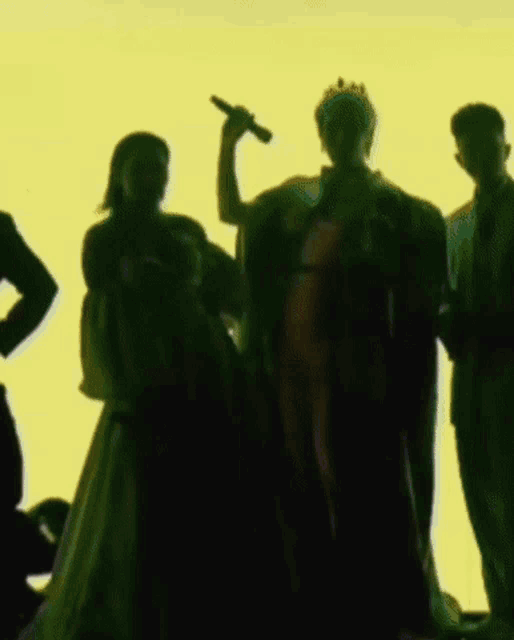 a woman in a white dress is holding a microphone while standing next to two men in suits .