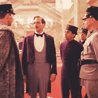 a group of men in suits and hats are standing in a hallway